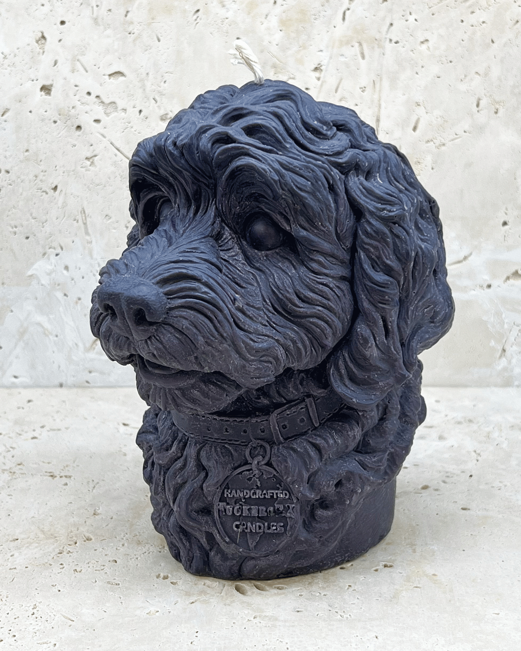 A black Cockerpoo dog head moulded candle side view