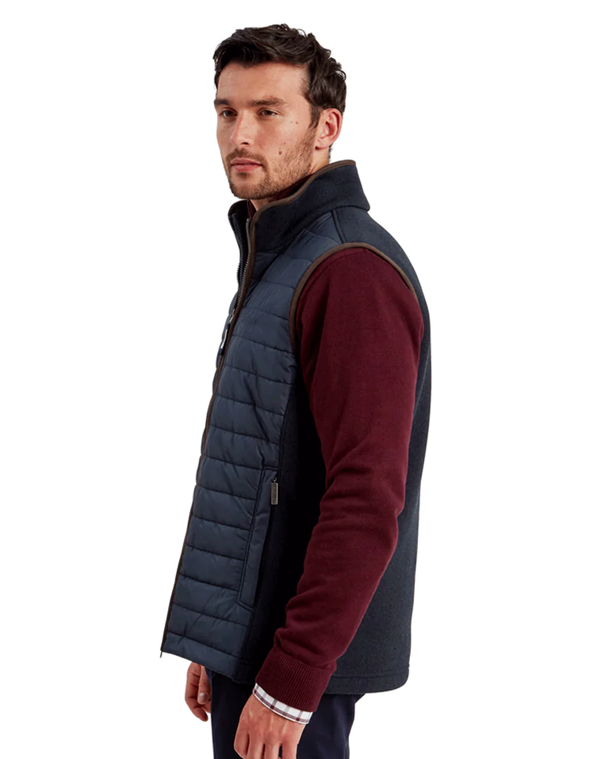 A side view of man wearing a burgundy jumper with a Schoffel Oakham Hybrid gilet.