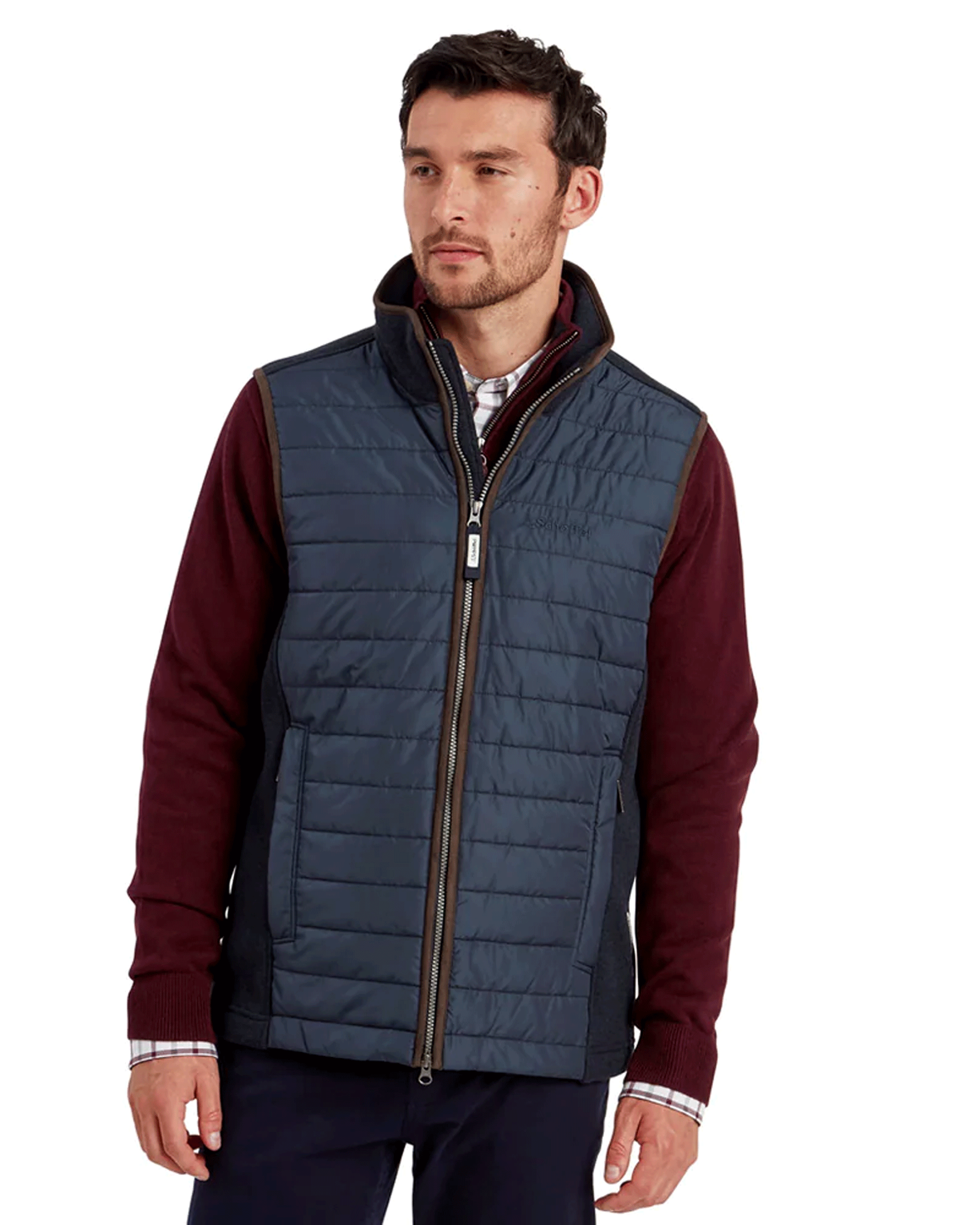 A man wearing a burgundy jumper with a Schoffel Oakham Hybrid gilet.