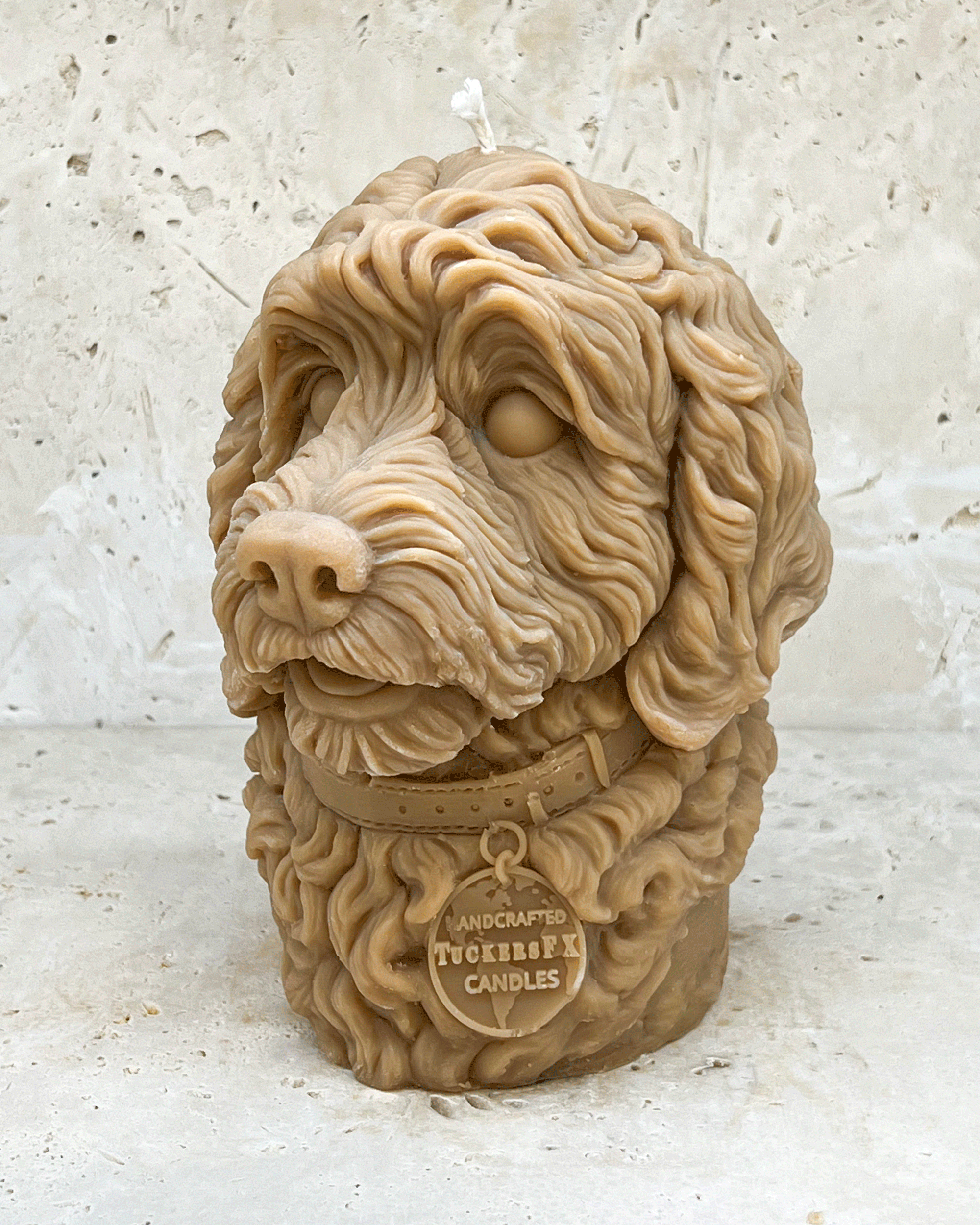 A golden coloured Cockerpoo dog head moulded candle side view