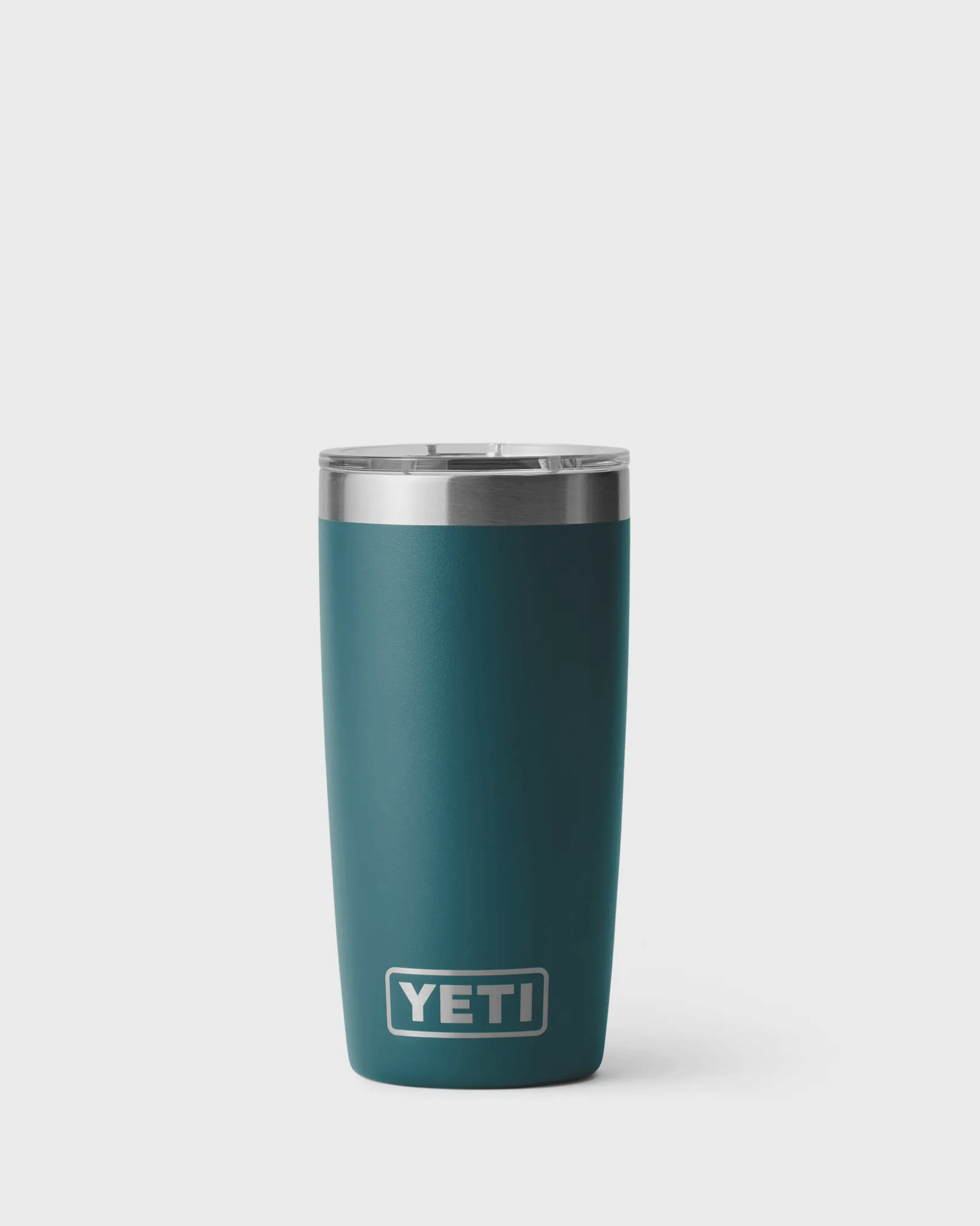 A teal green insulated YETI tumbler called Agave with a stainless steel rim and clear plastic lid, standing upright against a light grey background. The tumbler has a smooth matte finish, a slightly tapered shape, and the YETI logo near the bottom front.